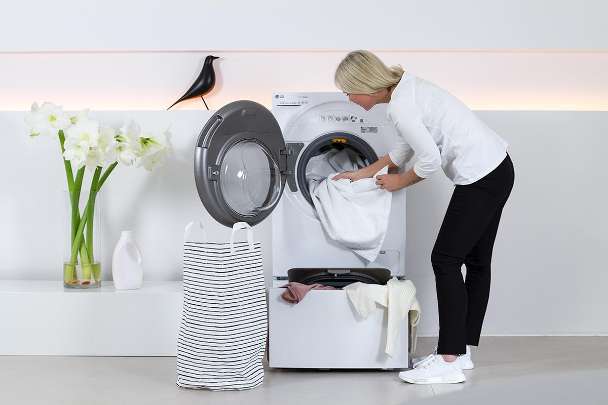 women standing beside a washer, washing machine, laundry, white flowers, liquid laundry detergent bottle, picture from LG TwinWash blog post on lifetime-pieces.com