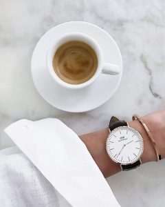 Daniel Wellington cuff and classic watch arm white shirt marble table with coffee Blog post on Lifetime-pieces.com