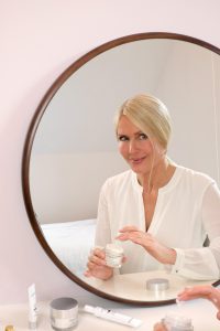 blonde, woman, sitting, in front of a mirror, neutrogena, cellular boost, skincare